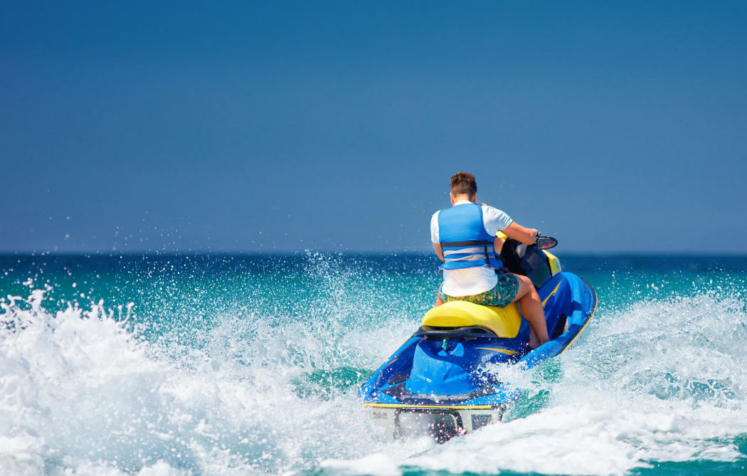 young adult man running the wave on jet ski during summer vacation