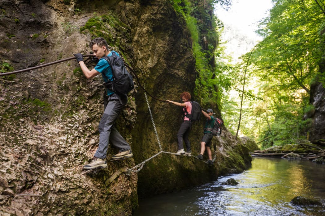 A photo of father hiking with his children above a river