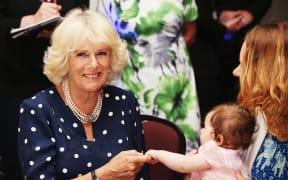 The Duchess of Cornwall interacts with a baby at Auckland charity Bellyfull