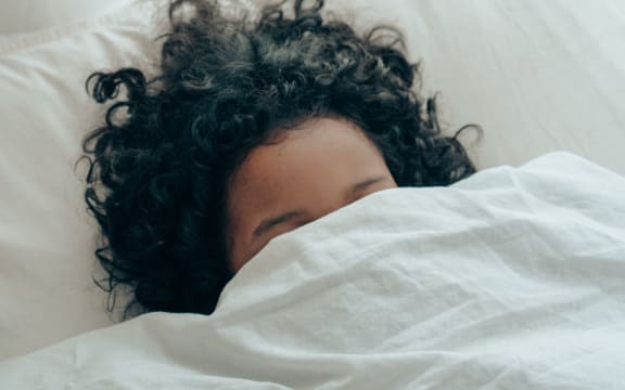 woman hiding under bedsheet