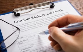 Close-up Of Person Hand Filling Criminal Background Check Application Form