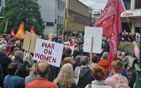 In Dunedin, more than 100 protesters have packed John Wickliffe Square, chanting "What's outrageous? Gendered wages"
