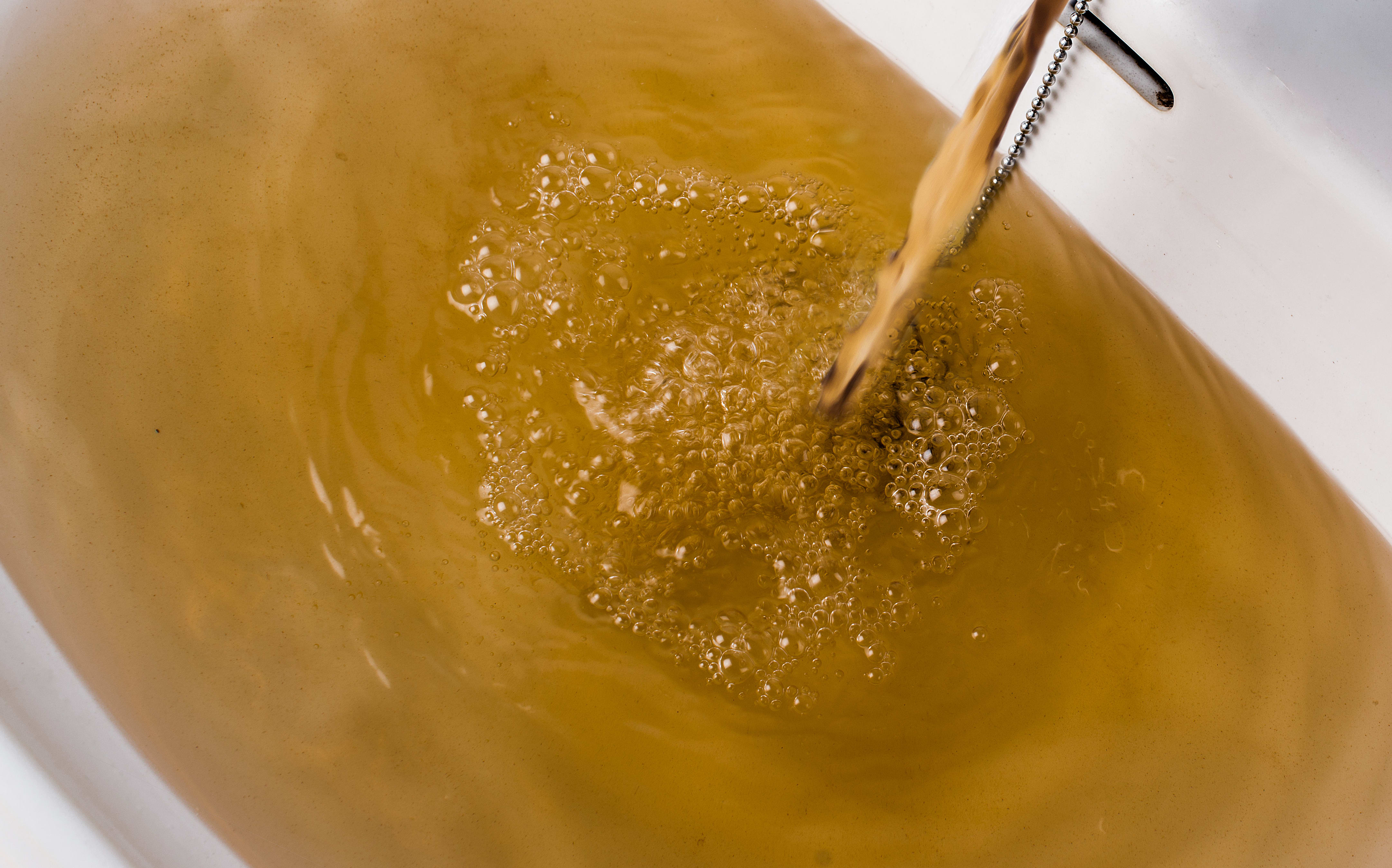Dirty brown water running into a white sink. Looks very unhealthy,