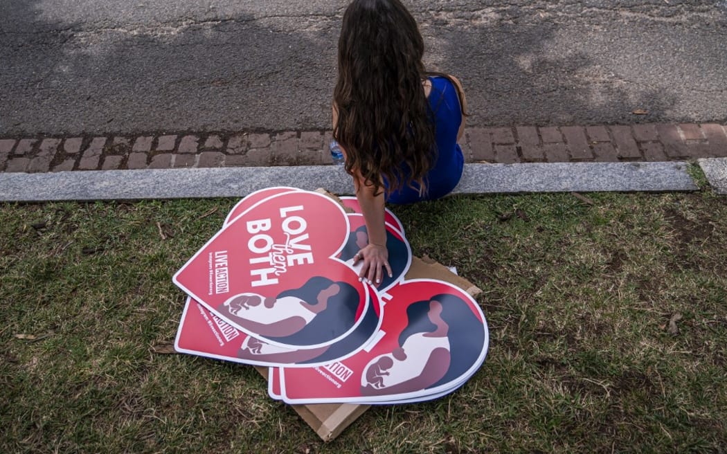 WASHINGTON, DC - JUNE 24: A woman rests next to anti-abortion posters in front of the U.S. Supreme Court after the Court announced a ruling in the Dobbs v Jackson Women's Health Organization case on June 24, 2022 in Washington, DC. The Court's decision in the Dobbs v Jackson Women's Health case overturns the landmark 50-year-old Roe v Wade case, removing a federal right to an abortion.   Nathan Howard/Getty Images/AFP (Photo by Nathan Howard / GETTY IMAGES NORTH AMERICA / Getty Images via AFP)