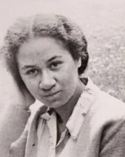 A soft black and white photo of a young Māori woman holding her hand to her head.