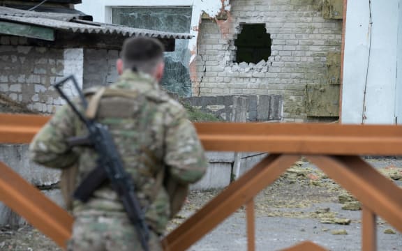 A Ukrainian soldier looks at debris after the reported shelling of a kindergarten in the settlement of Stanytsia Luhanska, on February 17, 2022.