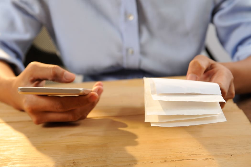 Closeup of person calculating or paying bills. Woman using smartphone. Online payment concept. Cropped view.