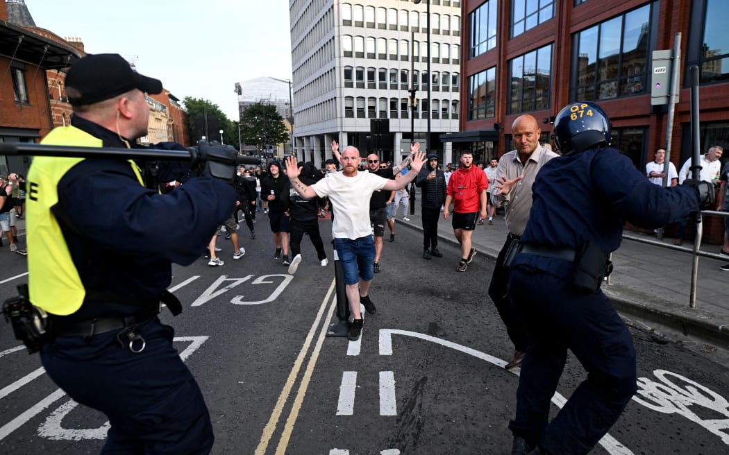 Riot police face protestors in Bristol, southern England, on August 3, 2024 during the 'Enough is Enough' demonstration held in reaction to the fatal stabbings in Southport on July 29. UK police prepared for planned far-right protests and other demonstrations this weekend, after two nights of unrest in several English towns and cities following a mass stabbing that killed three young girls. (Photo by JUSTIN TALLIS / AFP)