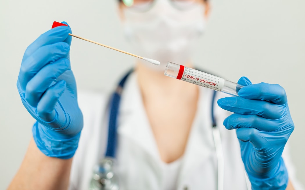 Test for coronavirus Covid-19. Female doctor or nurse doing lab analysis of a nasal swab in a hospital laboratory. Medical technologist holding a COVID-19 smear kit, wearing protective gloves from