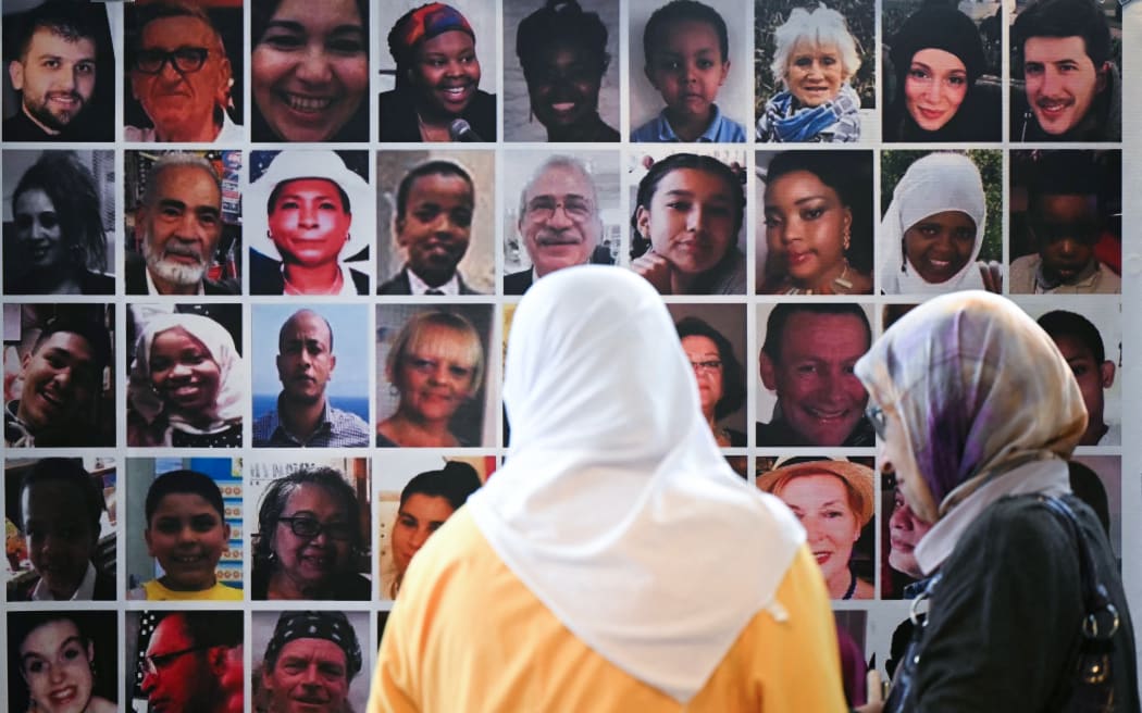 Menana Jabari (L) a relative of the victims of the Grenfell Tower fire disaster looks at a wall displaying pictures of the 72 people killed by the blaze, as she arrives to attend a press conference at the Royal Lancaster Hotel, in London, on September 4, 2024 following the publication of the Grenfell Tower Inquiry. The UK's Grenfell Tower fire disaster that killed 72 people in 2017 was the "culmination of decades of failure" by government and construction industry bodies, a damning final report said on September 4, 2024. The report, marking the end of a long-running two-part inquiry, also accused firms that supplied the cladding and other materials for the residential high-rise of "systematic dishonesty". (Photo by JUSTIN TALLIS / AFP)