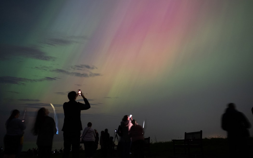 People visit St Mary's lighthouse in Whitley Bay to see the aurora borealis, commonly known as the northern lights, in May 2024 in Whitley Bay, England.