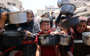 Palestinians crowd at a lentil soup distribution point in Gaza City in the northern Gaza Strip on July 27, 2025. (Photo by Omar AL-QATTAA / AFP)