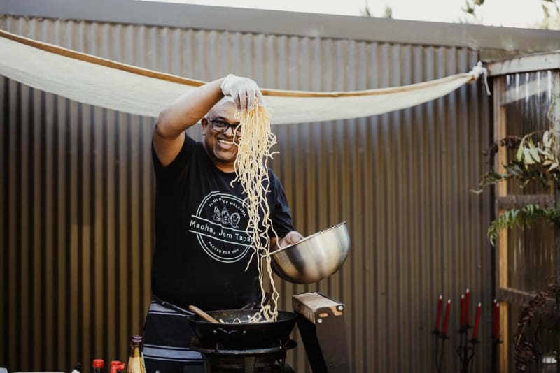 Muthuvelu Supramaniam puts noodles into a wok.