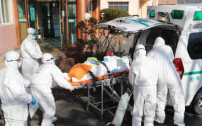 Medical workers wearing protective gear transfer a suspected coronavirus patient  to another hospital from Daenam Hospital where a total of 16 infections have now been identified.