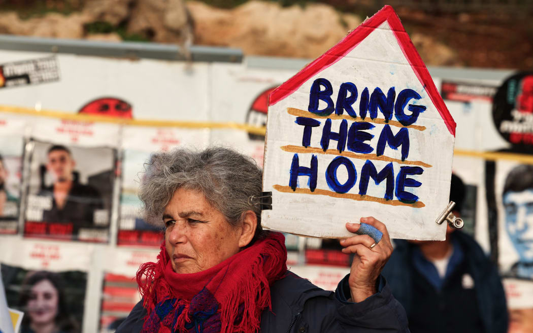 A protester lifts a placard during a rally demanding the release of Israelis taken hostage a hundred days earlier by the Palestinian Hamas movement on October 7, outside the Israeli Parliament in Jerusalem on January 15, 2024. (Photo by Ahmad GHARABLI / AFP)