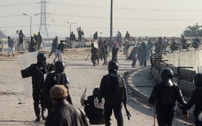 Pakistani protesters throw rocks toward riot policemen during a clash in Islamabad