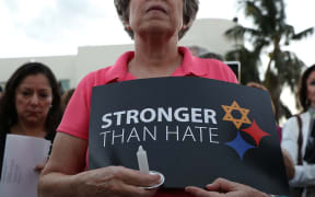 A person holds a sign that reads, 'Stronger than Hate,' as she joins with others for a Community-Wide Solidarity Vigil at the Holocaust Memorial Miami Beach to remember the victims of the mass shooting at a Pittsburgh temple.