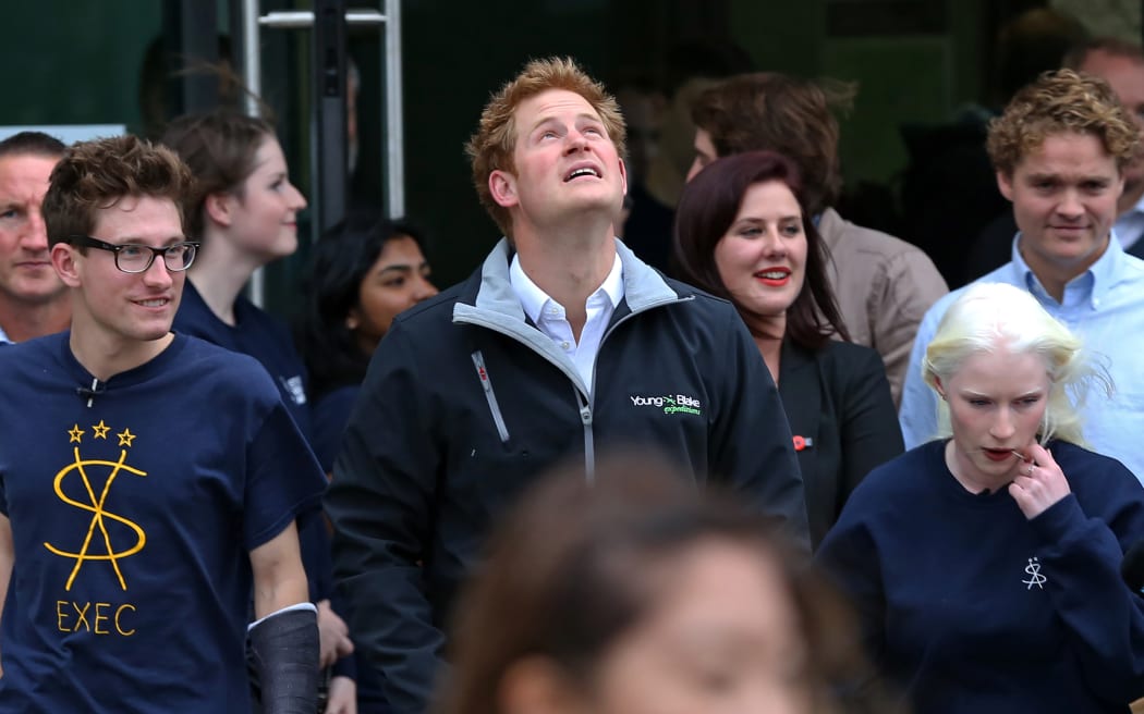 Prince Harry looking up at thunderous clouds about to downpour.