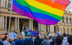 A protester waves a rainbow coloured flag at a marriage equality rally outside Town Hall in Sydney, Australia on August 9, 2015.