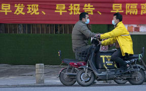 People ride scooters in a street in Wuhan,  Hubei Province, 16 February2020.