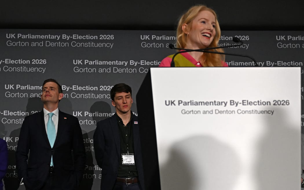 Reform UK candidate Matt Goodwin (L) listens as Green Party candidate Hannah Spencer gives her acceptance speech after winning the Gorton and Denton Parliamentary by-election, at Manchester Central Convention Complex in Manchester, northern England on February 27, 2026. Green candidate Hannah Spencer won the by-election in the Manchester suburb of Gorton and Denton with almost 15,000 votes as Labour slumped to third place behind the hard-right Reform UK party, which finished second.