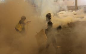Protesters run from tear gas fired by police after a march against a controversial extradition bill in Hong Kong on July 21, 2019