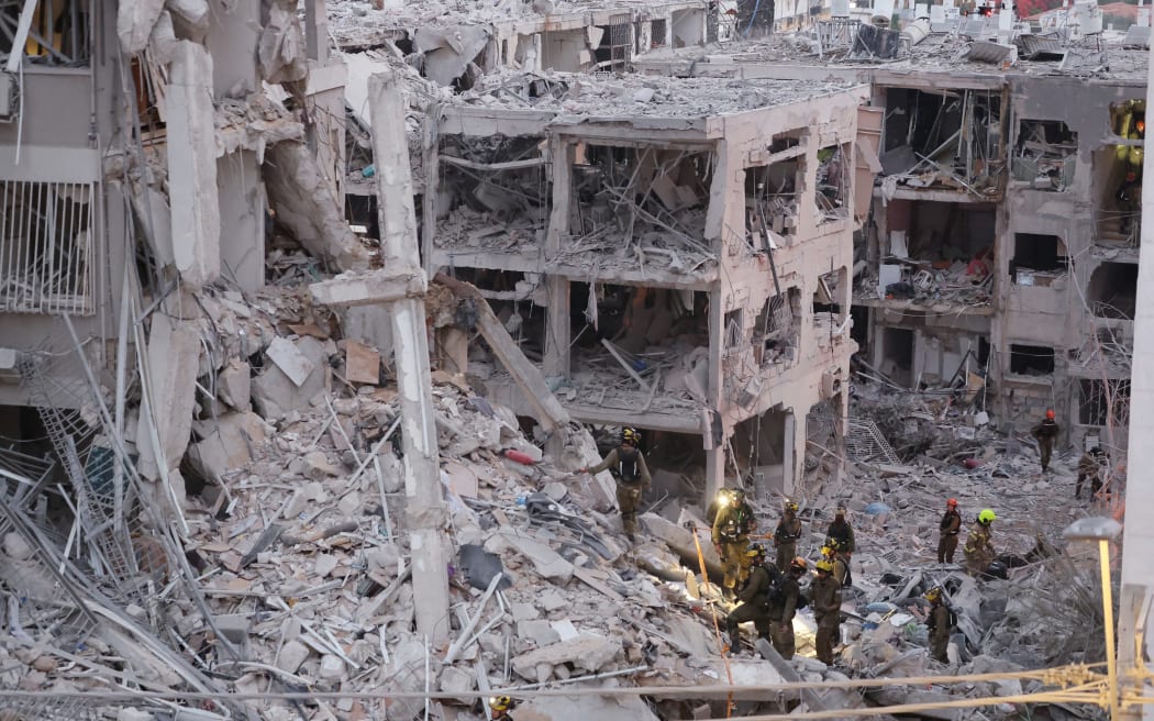 Responders work amid building rubble following a strike by an Iranian missile in the Israeli city of Bat Yam, south of Tel Aviv, early on June 15, 2025. Air raid sirens and booms rang out in Jerusalem and Tel Aviv early on June 15, AFP journalists said, as Israel and Iran exchanged fire for a third day. (Photo by Jack GUEZ / AFP)