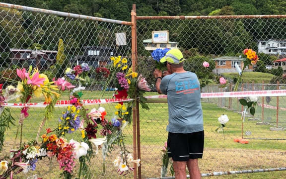 A local man places flowers from his garden on the Whakatāne boat ramp cordon.