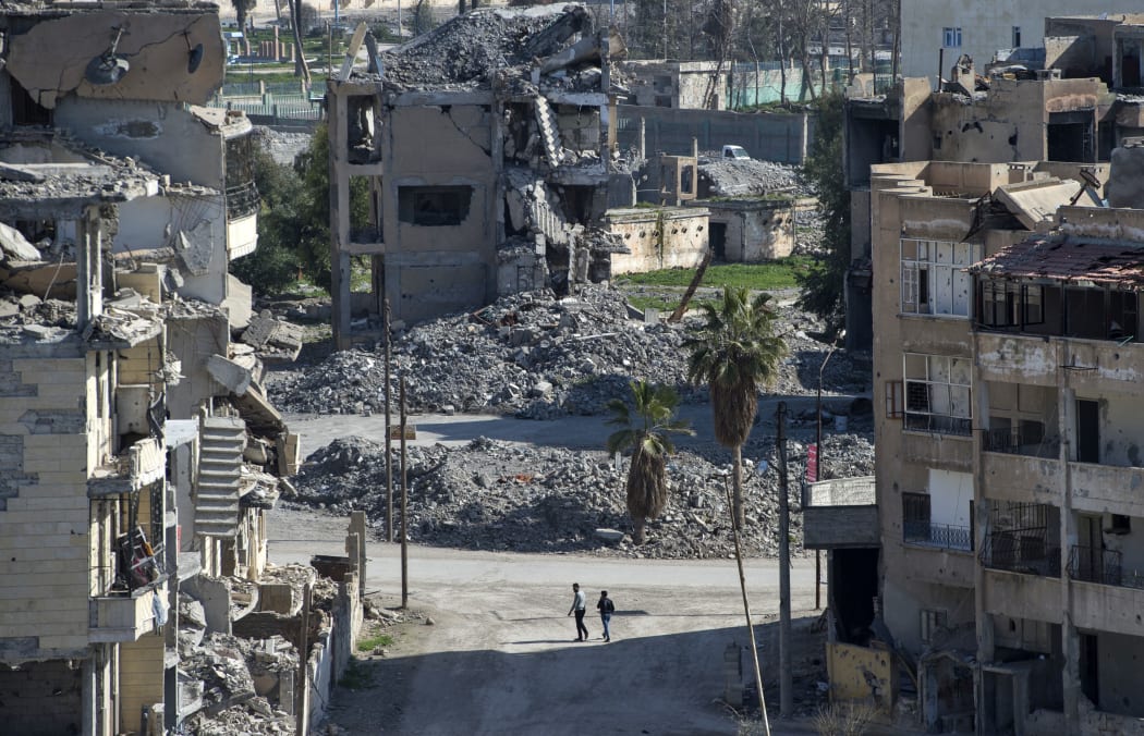 Syrian men walk amidst debris in the Islamic State (Isis) group's former Syrian capital of Raqqa.