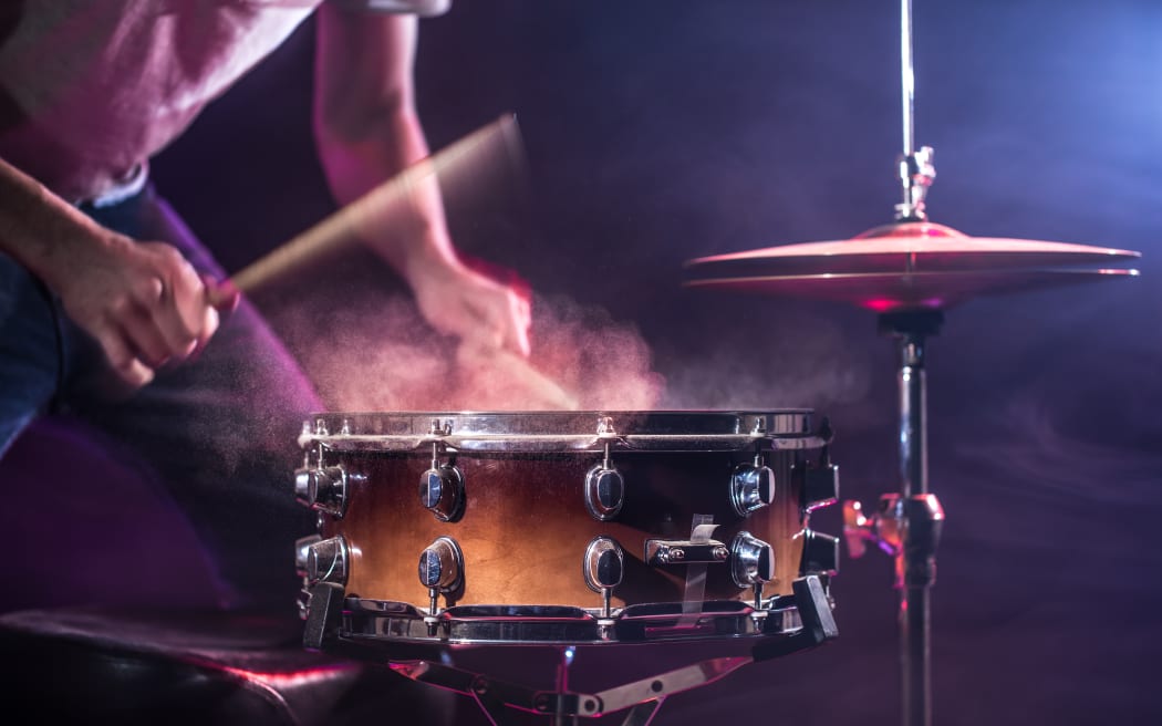 The drummer plays the drums. Beautiful blue and red background, with rays of light. Beautiful special effects smoke and lighting. The process of playing a musical instrument. The concept of music.