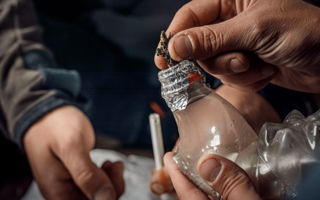 A man smokes drugs through a Bong bottle, a way of using cannabis