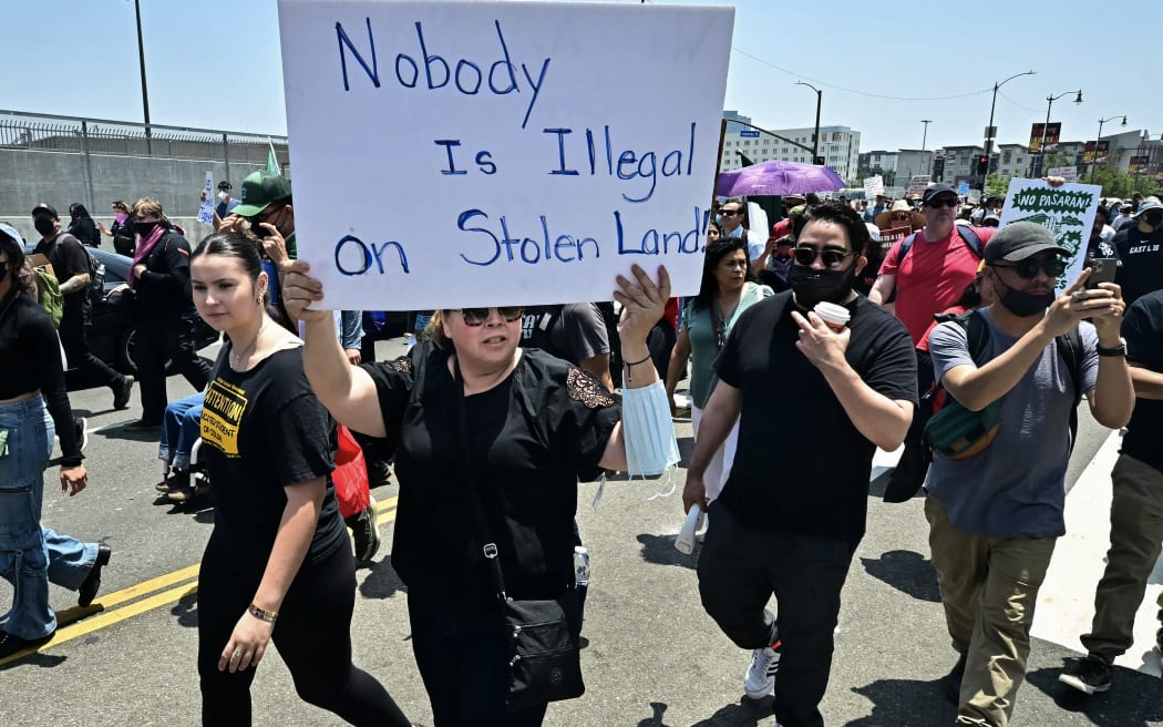 Immigration rights supporters, hold signs as they protests outside the Metropolitan Detention Center, MDC, in downtown Los Angeles, California on June 8, 2025. US President Donald Trump deployed 2,000 troops on June 7 to handle escalating protests against immigration enforcement raids in the Los Angeles area, a move the state's governor termed "purposefully inflammatory." Federal agents clashed with angry crowds in a Los Angeles suburb as protests stretched into a second night Saturday, shooting flash-bang grenades and shutting part of a freeway amid raids on undocumented migrants, reports said. (Photo by Frederic J. Brown / AFP)