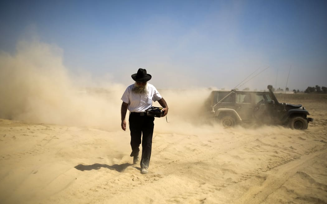 An ultra-Orthodox Jewish man carries prayer paraphernalia at a staging area outside the Gaza Strip.