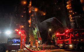 Firefighters spray water on flames as a major fire engulfs several apartment blocks at the Wang Fuk Court residential estate in Hong Kong's Tai Po district on November 26, 2025. A huge fire ripped through several high-rise blocks in a Hong Kong residential estate on November 26, killing at least 13 people, with media reporting that some residents were trapped inside. (Photo by AFP)