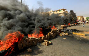 Sudanese protesters use bricks and burning tyres to block 60th Street in the capital Khartoum, to denounce overnight detentions by the army of members of Sudan's government, on October 25, 2021.