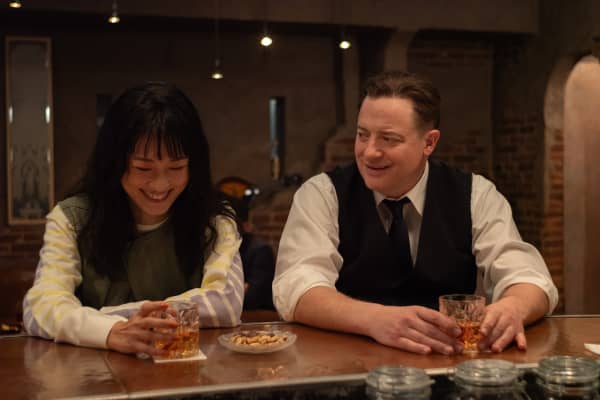 Mari Yamamoto as Aiko Nakajima and Brendan Fraser as Phillip Vanderploeg sitting in a bar drinking in the film Rental Family.
