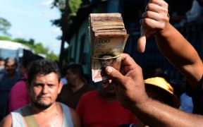 People hold up newly worthless 100-bolivar notes during a protest over lack of cash in the country.