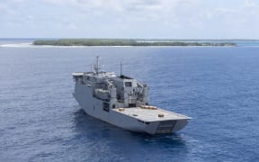 HMNZS Canterbury, pictured with Atafu atoll in the background.