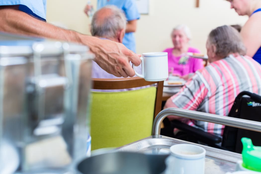 Nurse serving food in rest home for elderly.