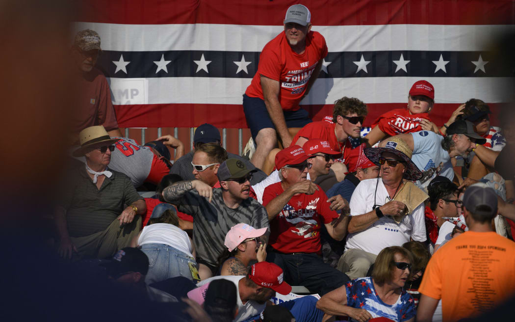 BUTLER, PENNSYLVANIA - JULY 13: Attendees duck from gunfire during a campaign rally for Republican presidential candidate, former U.S. President Donald Trump at Butler Farm Show Inc. on July 13, 2024 in Butler, Pennsylvania. Trump slumped before being whisked away by Secret Service with injuries visible to the side of his head. Butler County district attorney Richard Goldinger said the shooter and one audience member are dead and another was injured.   Jeff Swensen/Getty Images/AFP (Photo by JEFF SWENSEN / GETTY IMAGES NORTH AMERICA / Getty Images via AFP)
