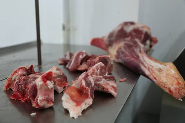 Slices of meat cut from a large portion at a halal butcher store.