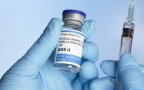 Nurse holding MMR (measles, mumps and rubella) vaccine vial in gloved hand with syringe. (Photo by SHERRY YATES YOUNG/SCIENCE PHOTO / SYO / Science Photo Library via AFP)