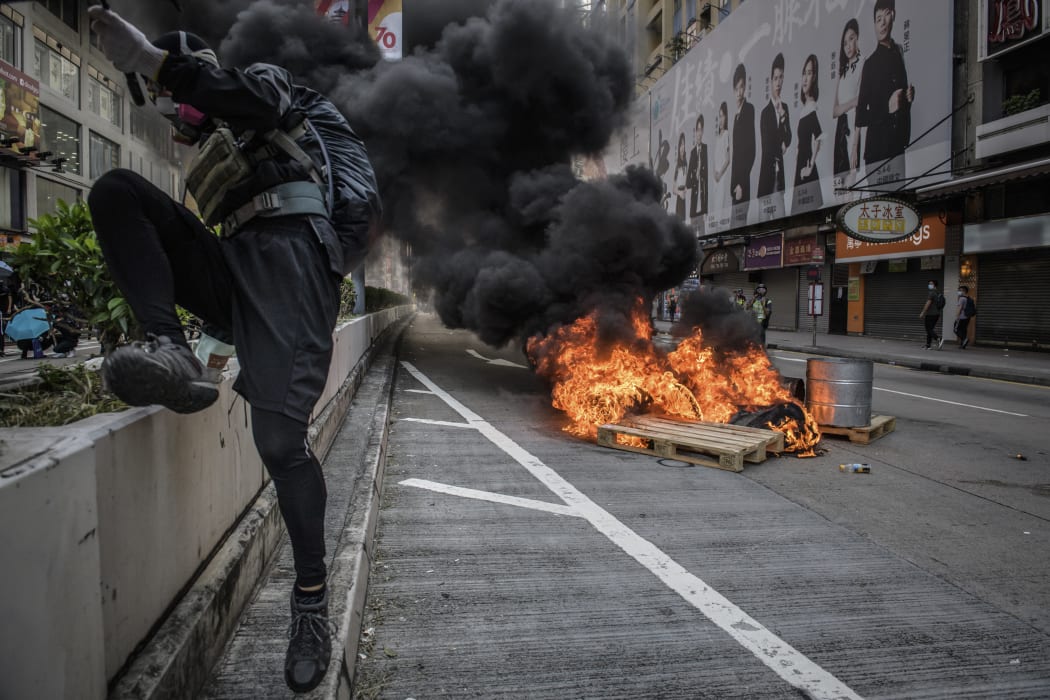 A protester jumps over a barrier after setting a fire on a road during a pro-democracy march in the Kowloon district in Hong Kong on October 20, 2019