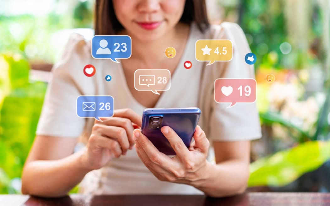 Young woman using mobile phone with social media interactions and notification icons.