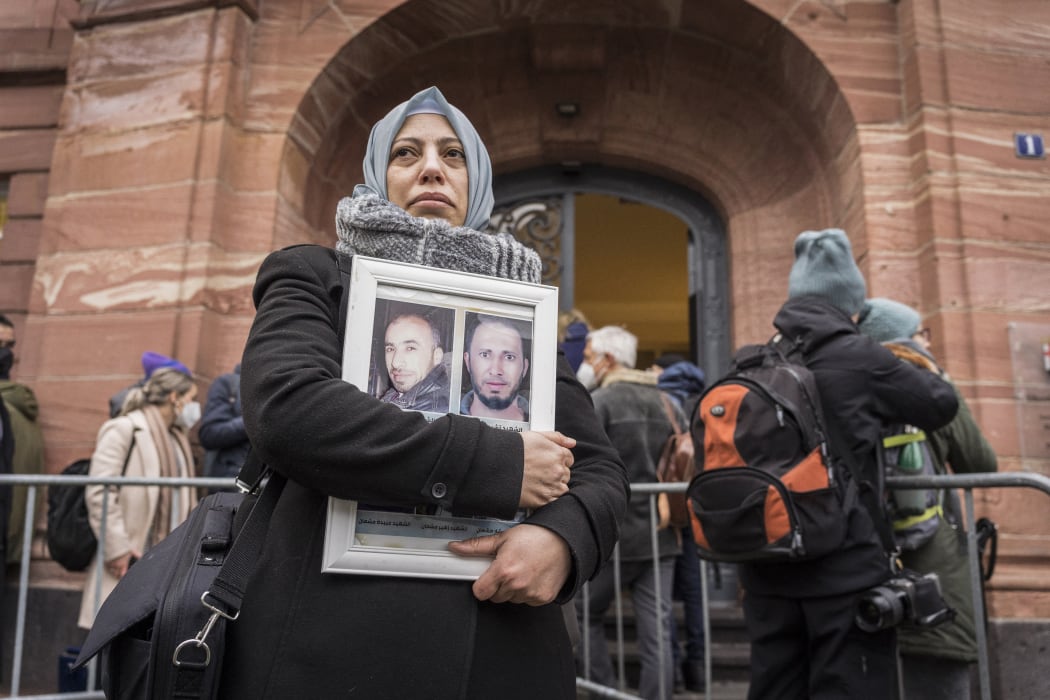 Syrian campaigner of the Caesar Families Association Yasmen Almashan holds pictures of victims of the Syrian regime as she and others wait outside the courthouse.