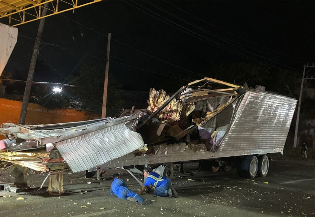 Workers remove the container from the trailer of a truck that crashed with migrants aboard during a road accident in Tuxtla Gutierrez, Chiapas state, Mexico