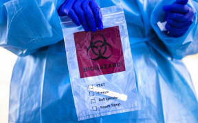Covid-19 tester holds a bag after administering a test at Echo Park Stadium on December 30, 2020 in Parker, Colorado.