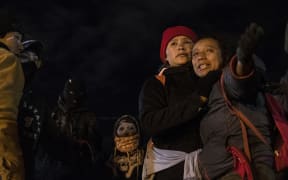 Central American migrants react after US border patrol officers threw tear gas at them while they were trying to jump over the US-Mexico border fence from Tijuana into the US.