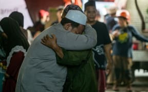 Relatives of missing students mourn as search and rescue operations continue at the Al Khoziny Islamic boarding school in Sidoarjo, East Java province on October 1, 2025, after a multi-storey building at the school collapsed. A second survivor was pulled on October 1, from the rubble of a school that collapsed in Indonesia two days earlier, authorities said. (Photo by Juni KRISWANTO / AFP)