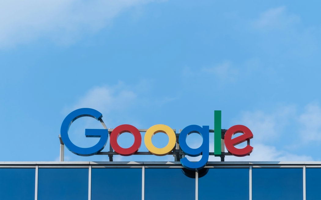 The Google logo sitting on top of a building with a blue sky in the background.